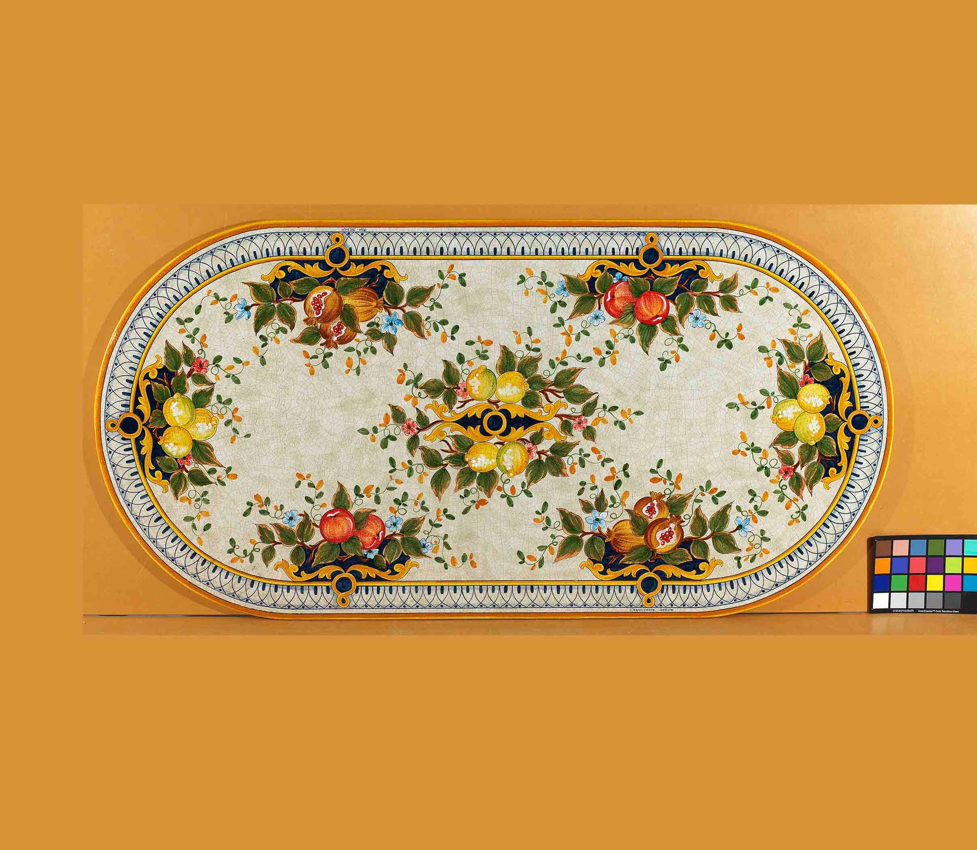 Birds eye view of the hand-painted Italian ceramic glaze Capri Frutteto lemon, pomegranate, and apple symmetrical pattern on an oval volcanic stone tabletop
