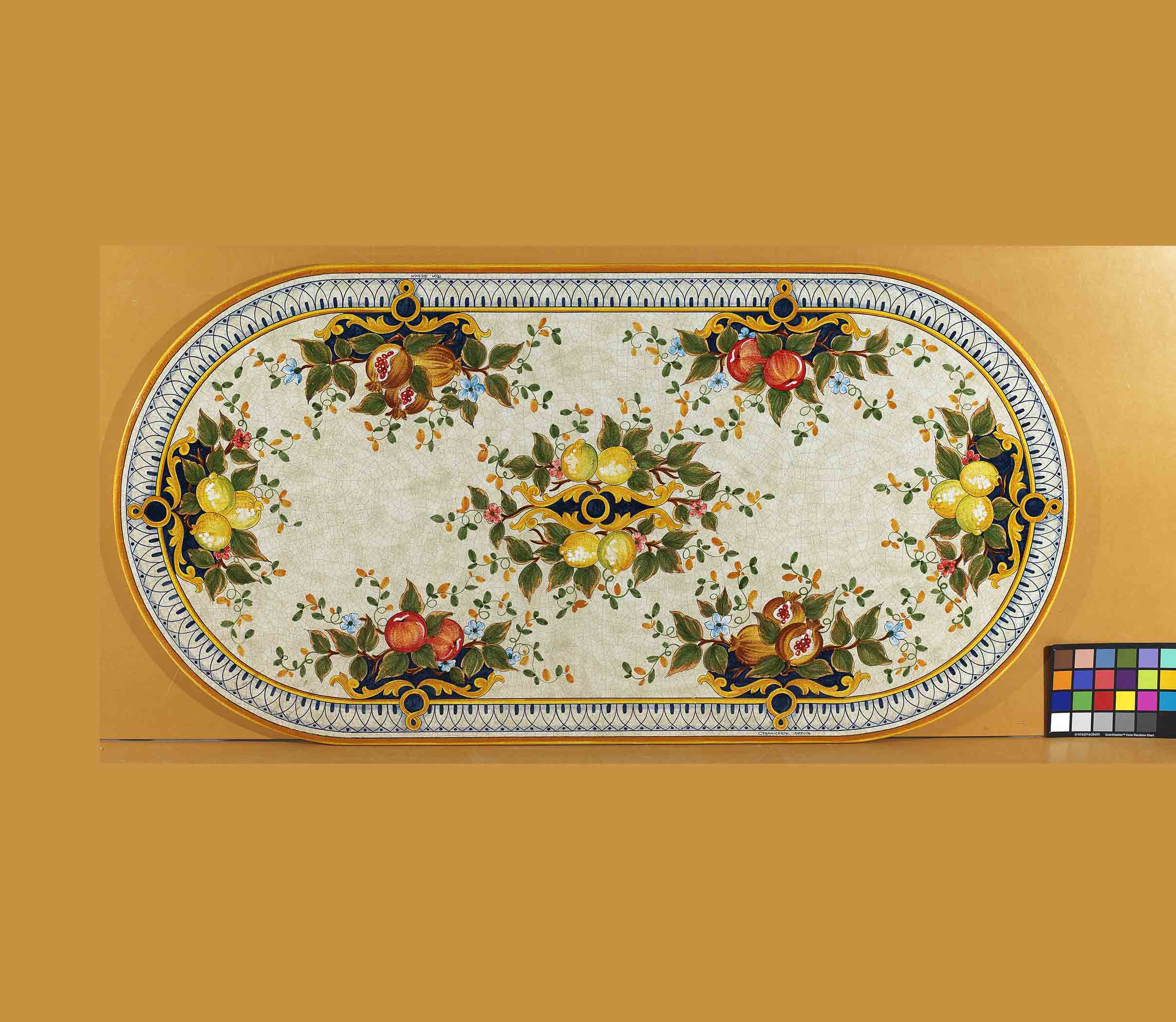 Birds eye view of the hand-painted Italian ceramic glaze Capri Frutteto lemon, pomegranate, and apple symmetrical pattern on an oval volcanic stone tabletop