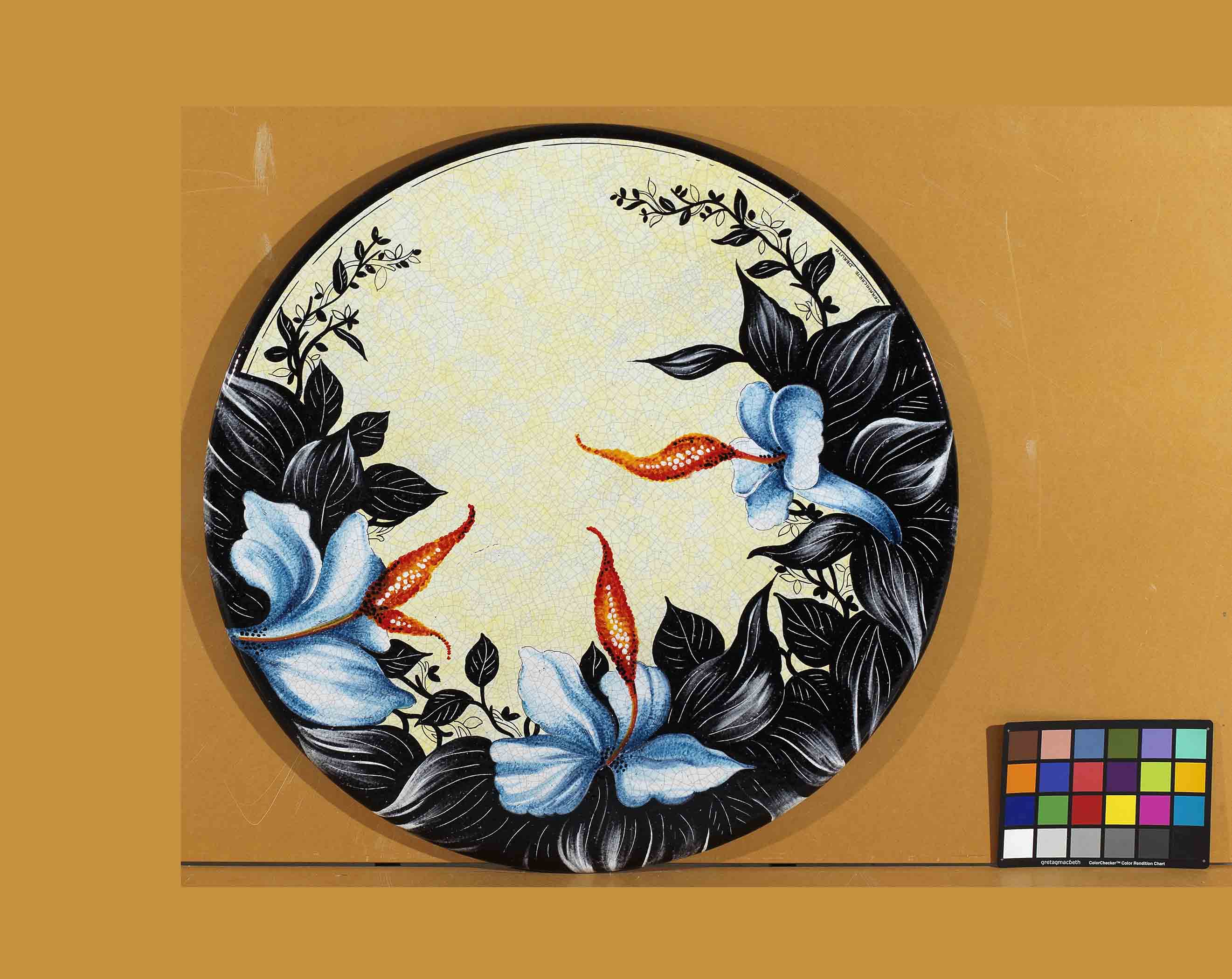 Birds eye view of the hand-painted Italian ceramic glaze Ischia Esotica exotic sky blue lilies and dramatic midnight black leaves on a round volcanic stone tabletop