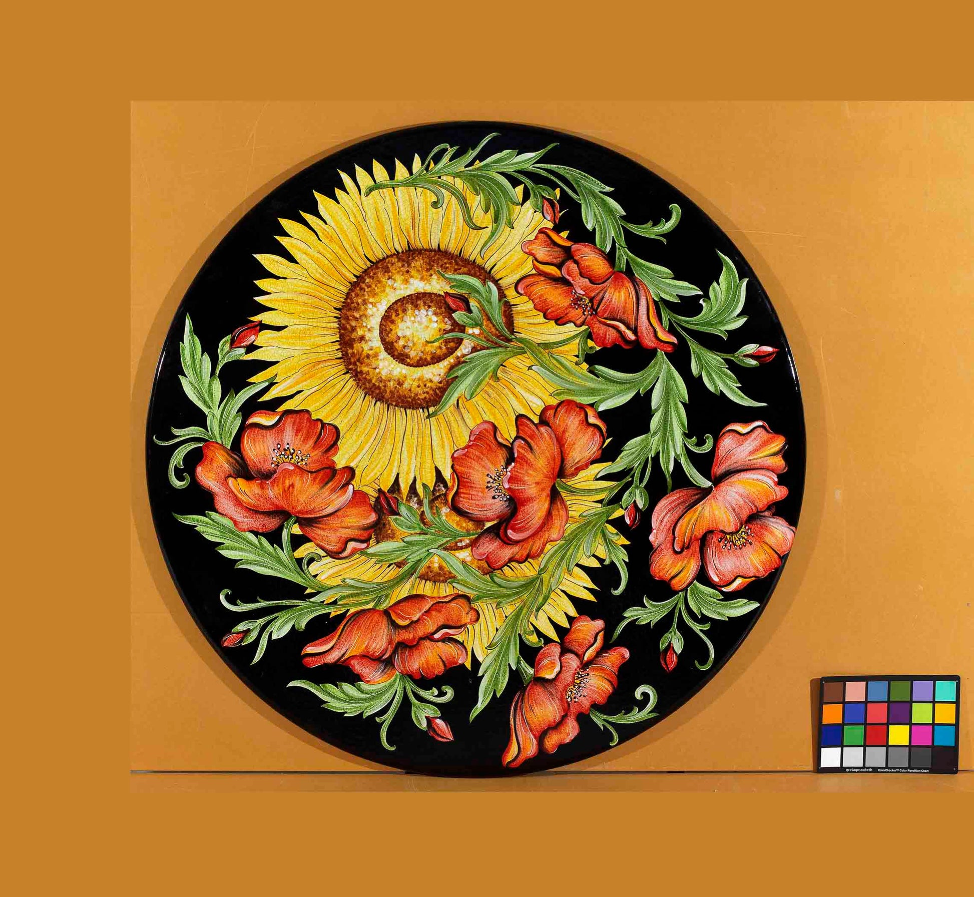 Birds eye view of the hand-painted Italian ceramic glaze Lucca Campagna massive yellow sunflower and coral red poppy layout on a glossy black round volcanic stone tabletop