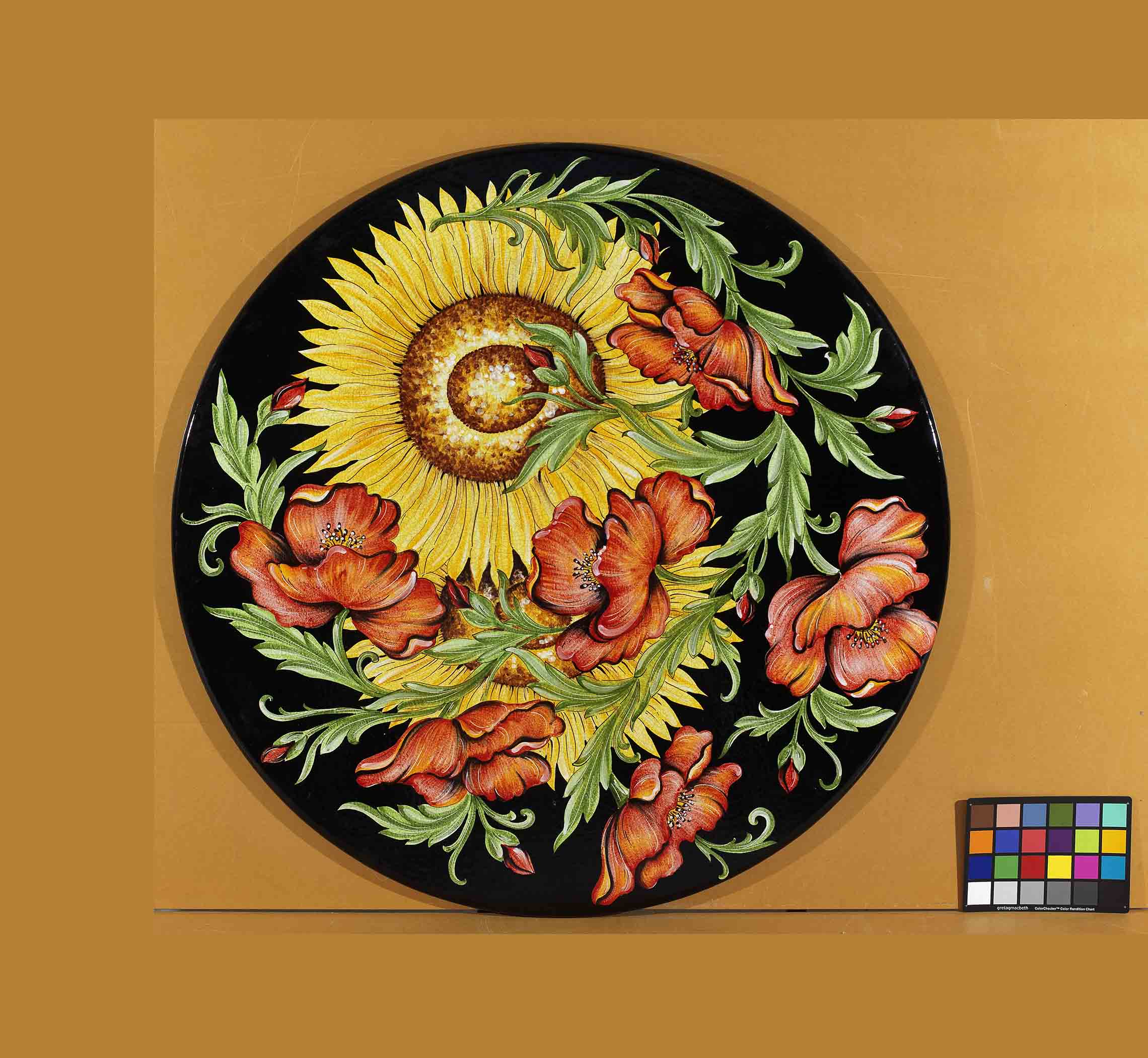 Birds eye view of the hand-painted Italian ceramic glaze Lucca Campagna massive yellow sunflower and coral red poppy layout on a glossy black round volcanic stone tabletop