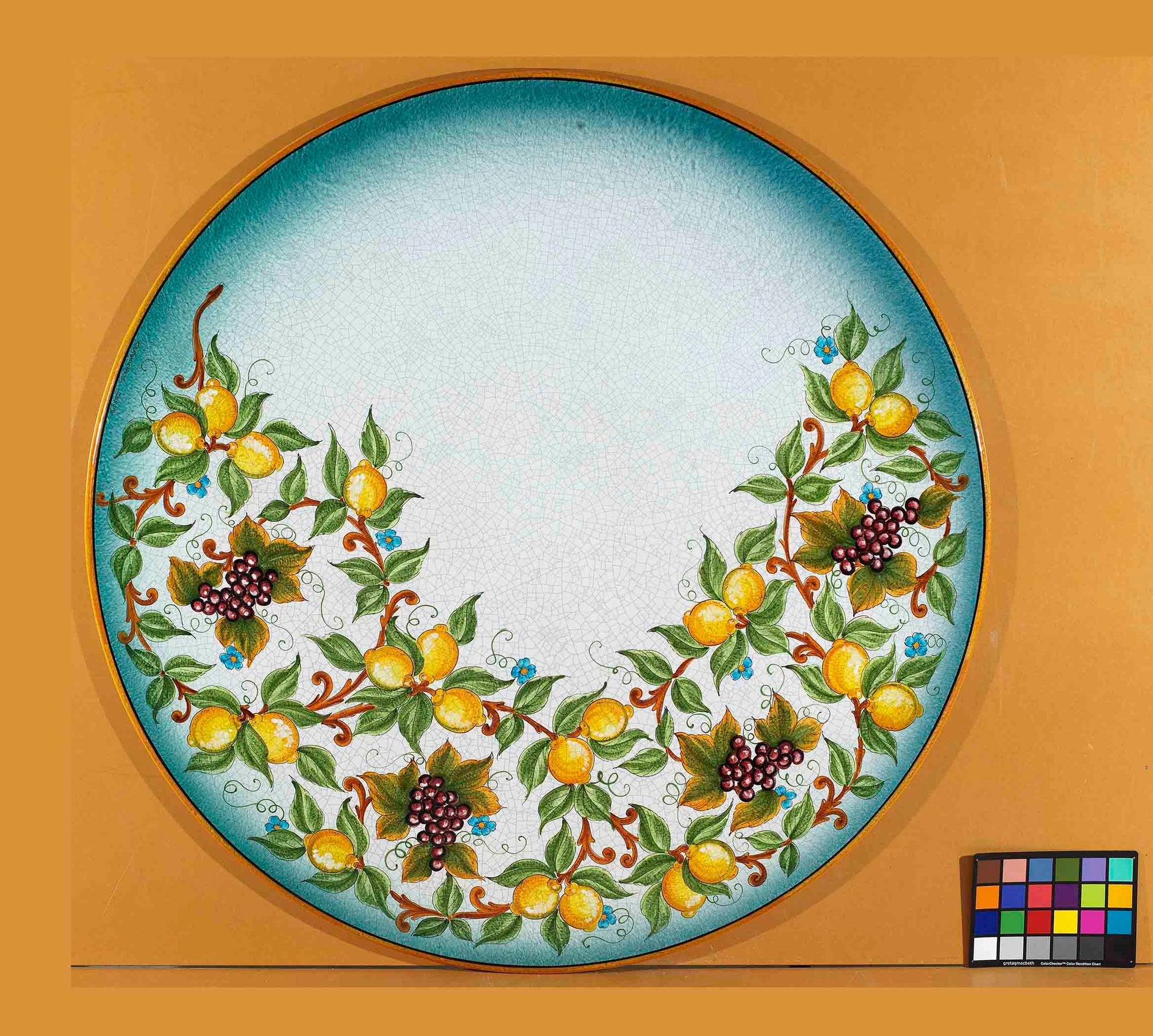 Birds eye view of the hand-painted Italian ceramic glaze Capri Riviera lemon and grape crescent garland on a round volcanic stone tabletop