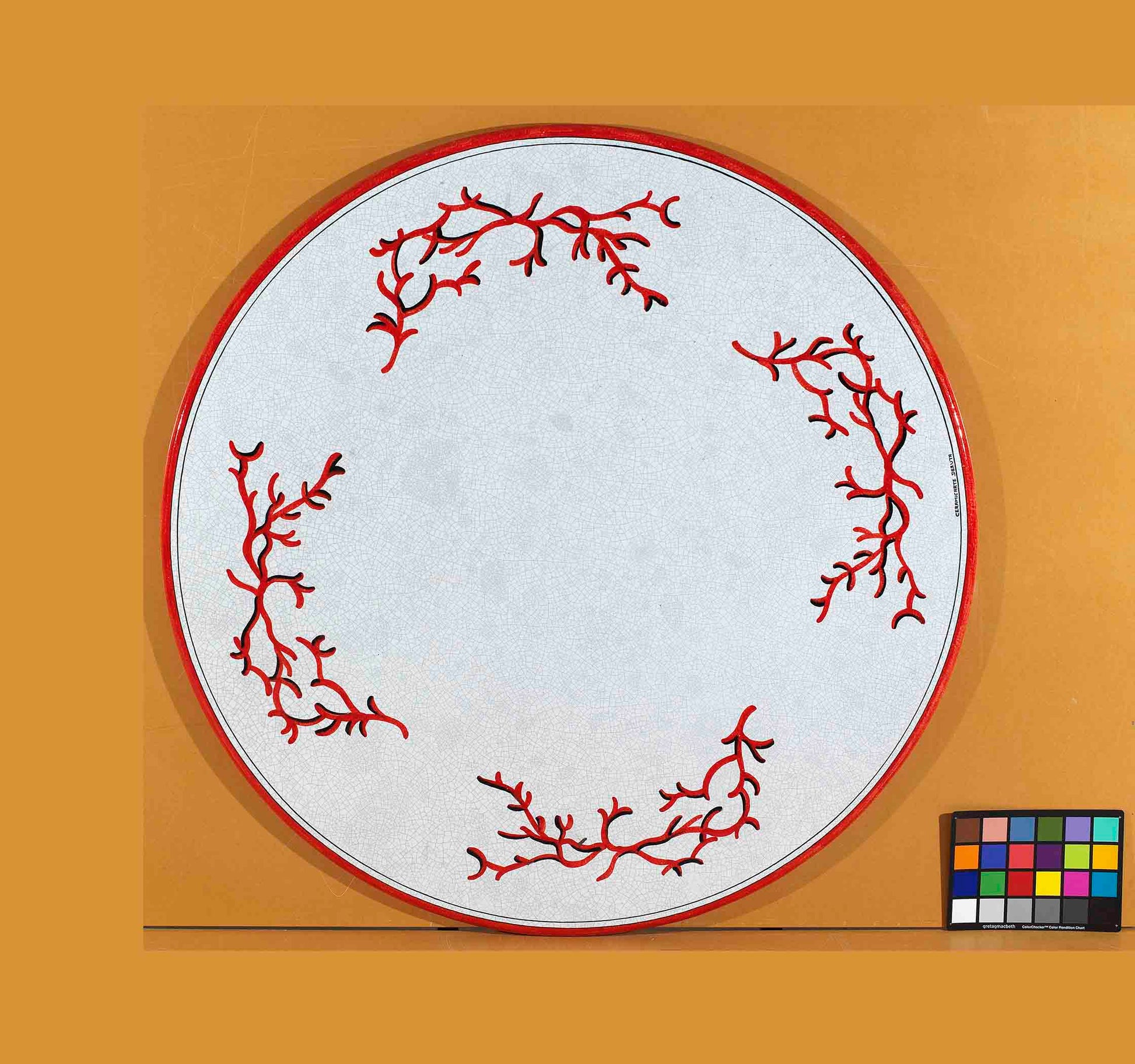 Birds eye view of the hand-painted Italian ceramic glaze Sardegna Corallo four-quadrant red coral pattern on a round volcanic stone tabletop