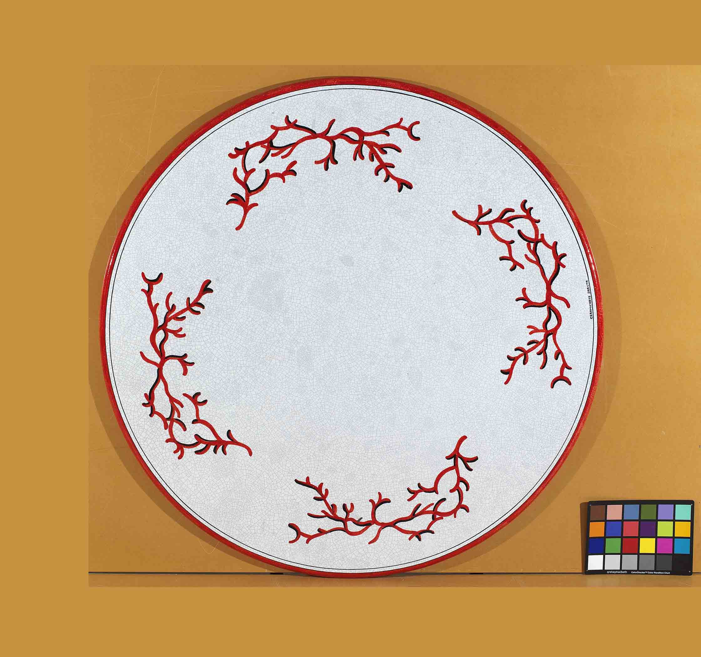 Birds eye view of the hand-painted Italian ceramic glaze Sardegna Corallo four-quadrant red coral pattern on a round volcanic stone tabletop