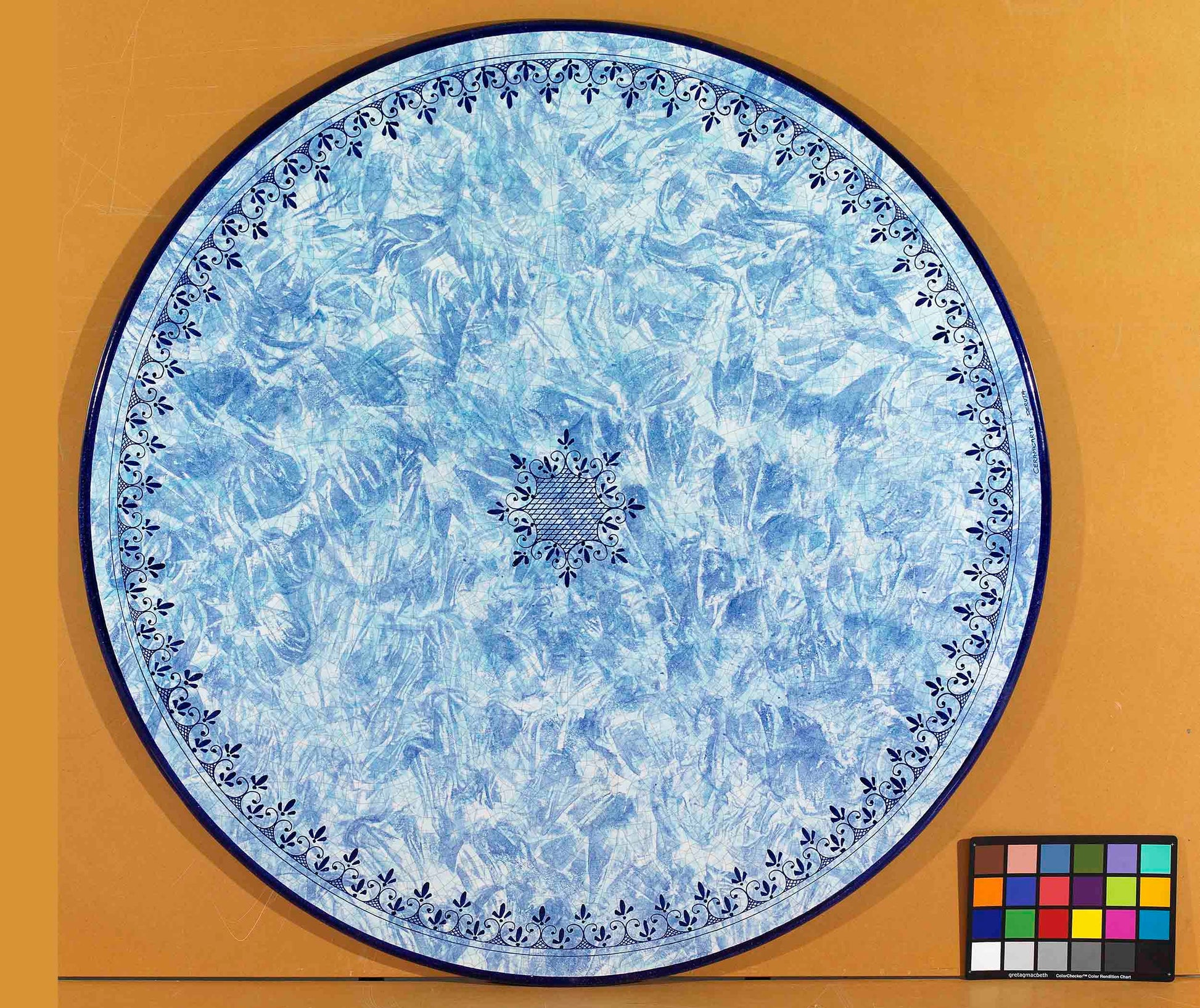 Birds eye view of the hand-painted Italian ceramic glaze Amalfi Marina central lattice medallion and blue scroll border on a round volcanic stone tabletop