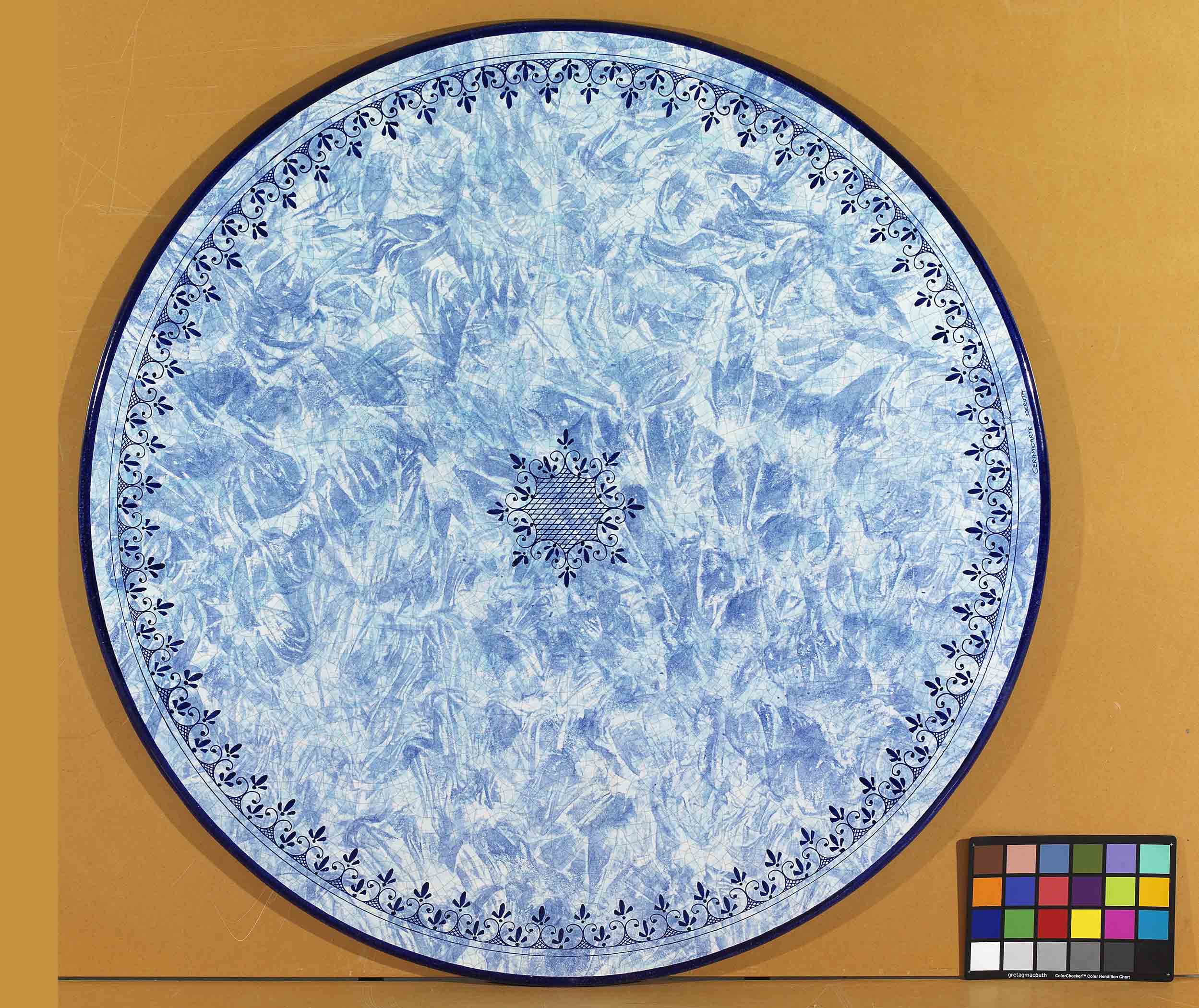 Birds eye view of the hand-painted Italian ceramic glaze Amalfi Marina central lattice medallion and blue scroll border on a round volcanic stone tabletop