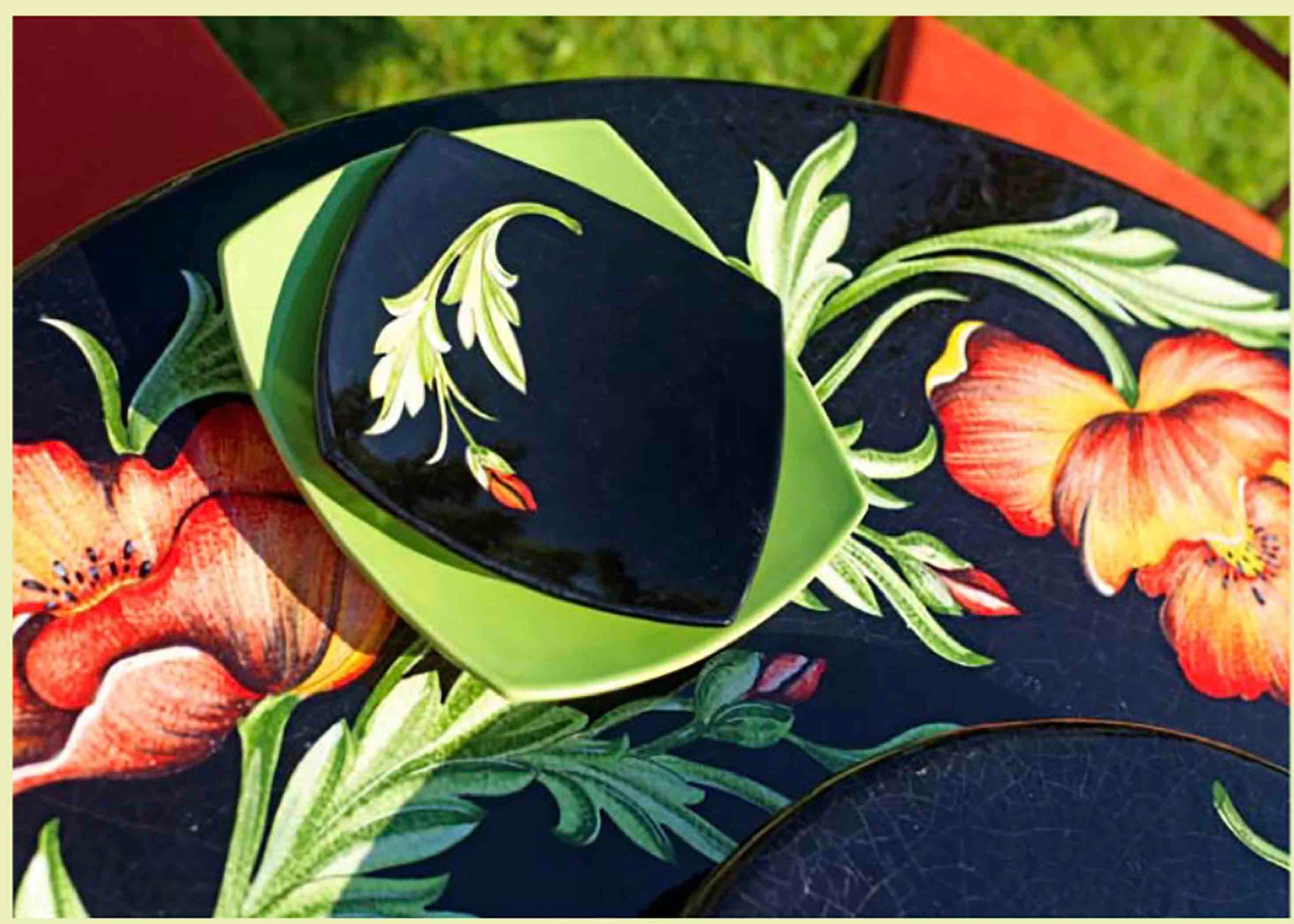 Birds eye view of the hand-painted Italian ceramic glaze Milano Papaveri large orange and red poppies on a glossy black round volcanic stone tabletop