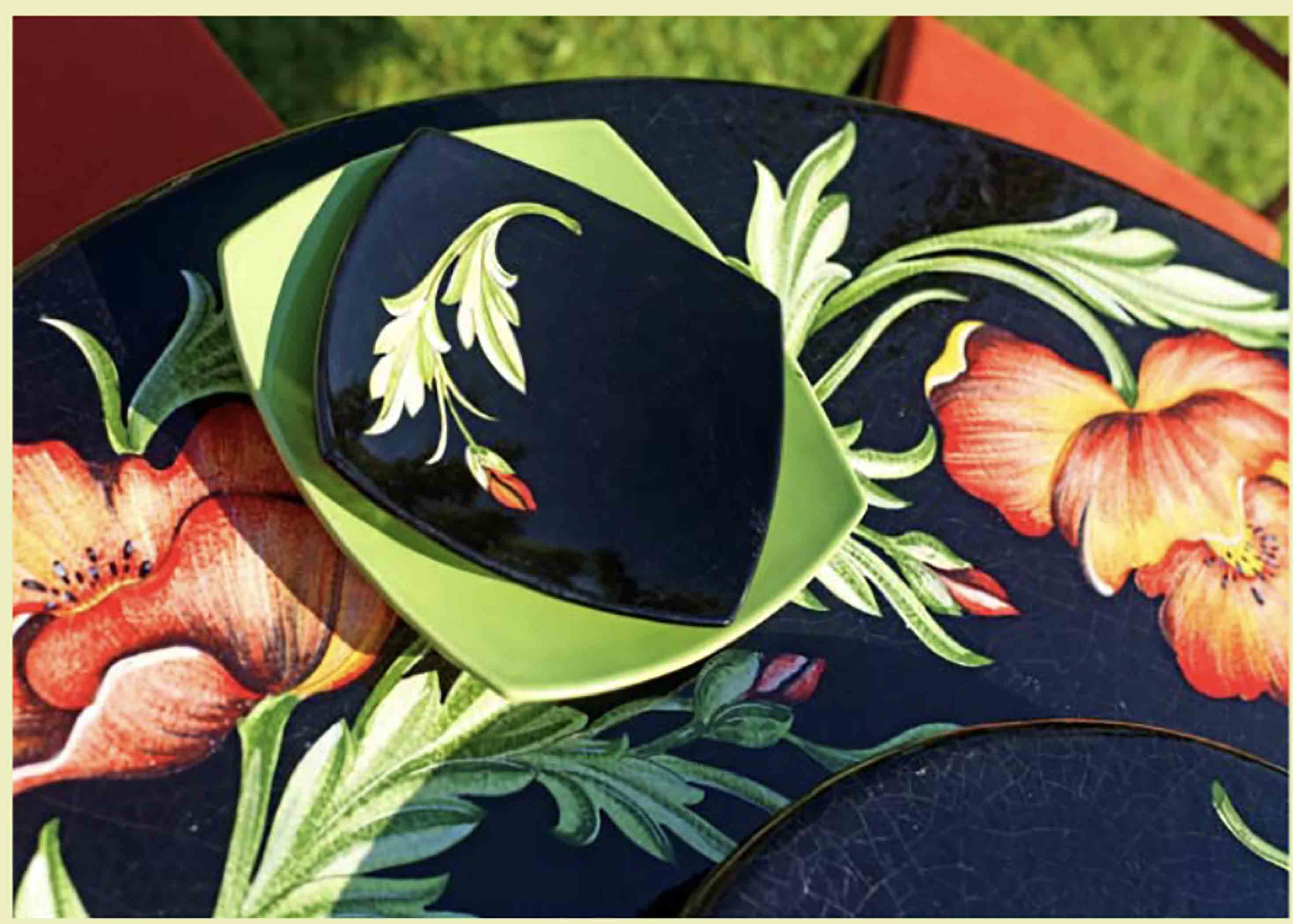 Birds eye view of the hand-painted Italian ceramic glaze Milano Papaveri large orange and red poppies on a glossy black round volcanic stone tabletop