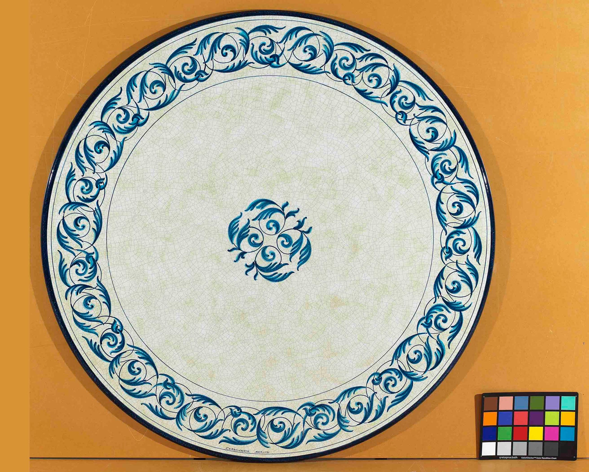 Birds eye view of the hand-painted Italian ceramic glaze Portofino Azzurro central rosette and monochrome blue scroll border on a round volcanic stone tabletop