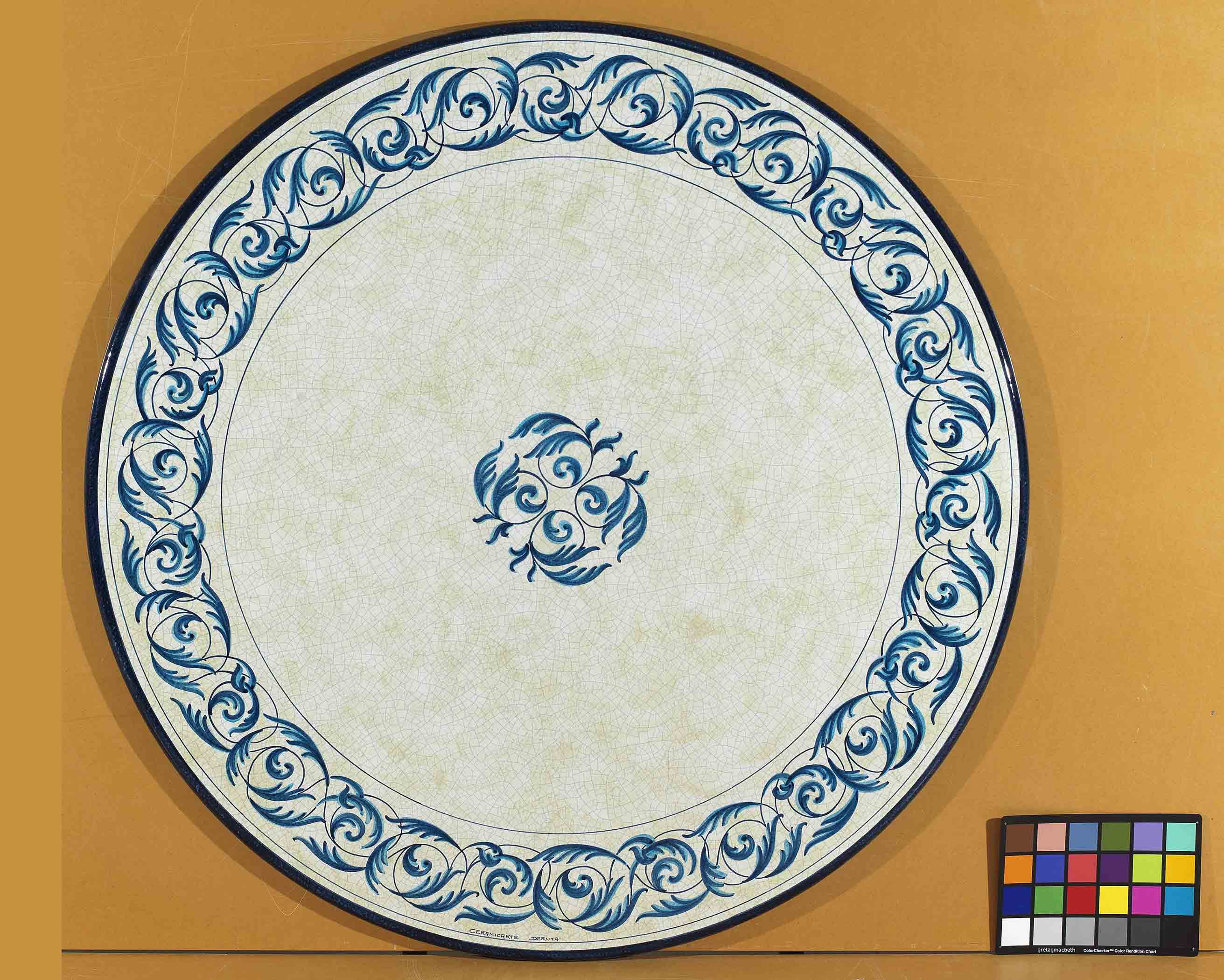 Birds eye view of the hand-painted Italian ceramic glaze Portofino Azzurro central rosette and monochrome blue scroll border on a round volcanic stone tabletop