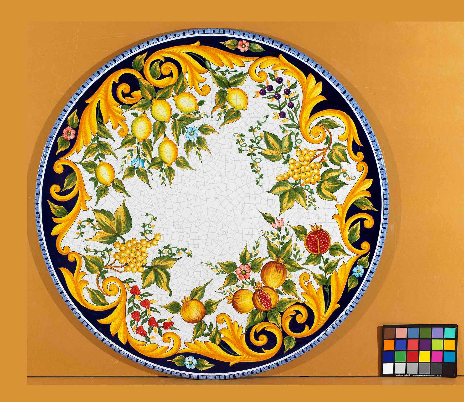 Birds eye view of the hand-painted Italian ceramic glaze Sorrento Rinascimento majestic acanthus scrolls and perimeter fruit harvest pattern on an volcanic stone tabletop