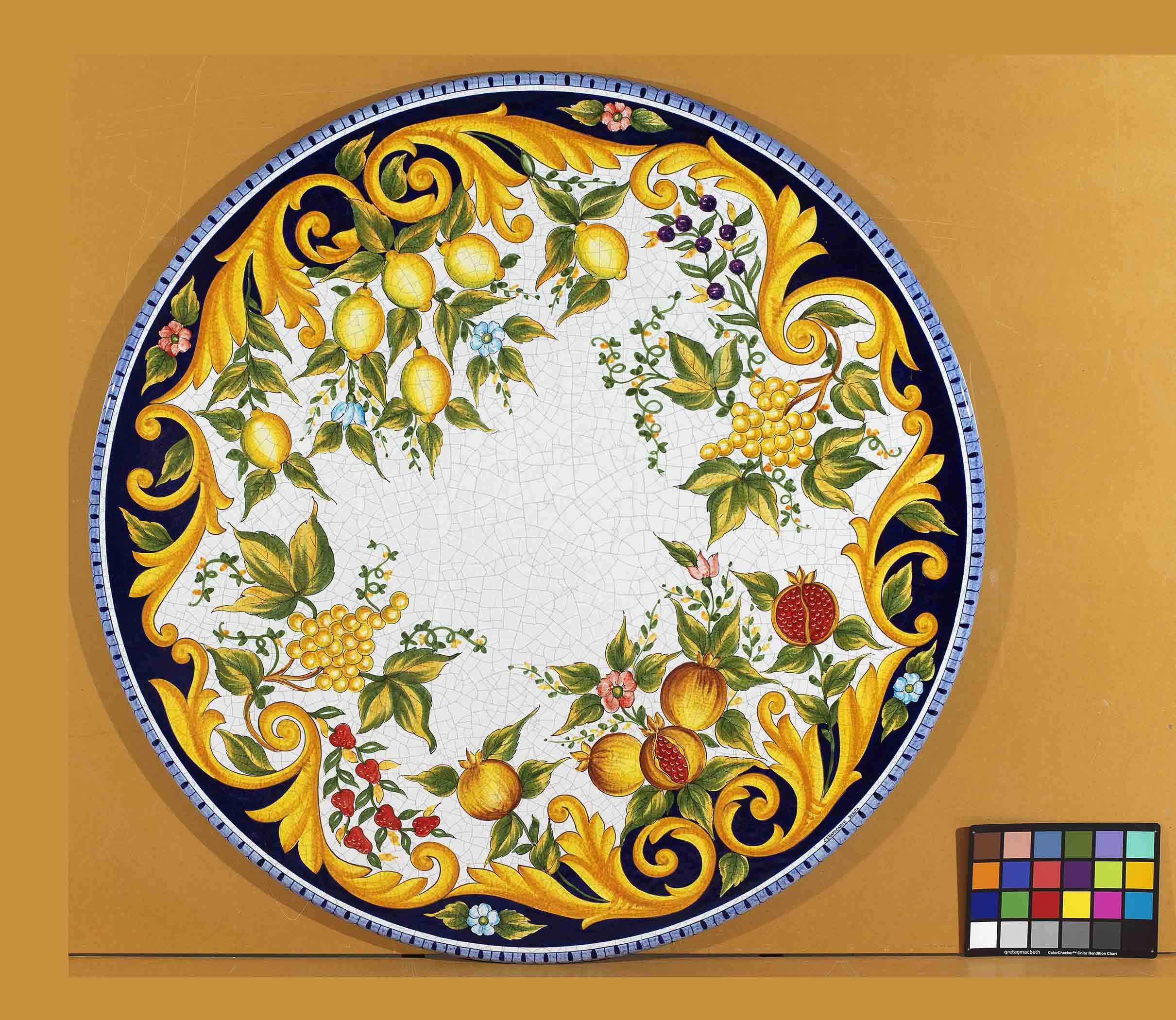 Birds eye view of the hand-painted Italian ceramic glaze Sorrento Rinascimento majestic acanthus scrolls and perimeter fruit harvest pattern on an volcanic stone tabletop