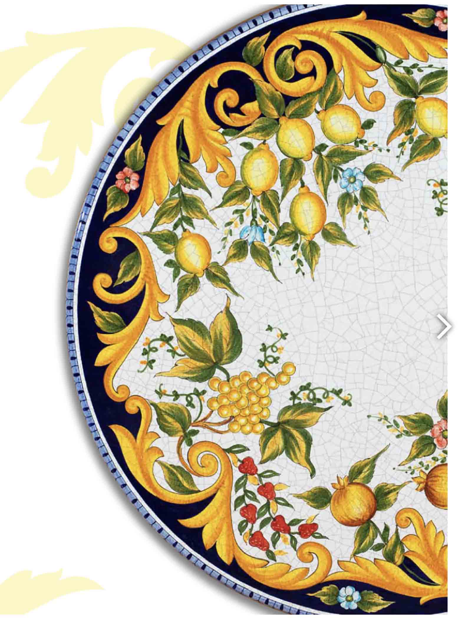Close up detail of the heavy golden renaissance scrolls, detailed pomegranates and white grapes, and beautiful craquelé texture on the Sorrento Rinascimento oval volcanic stone table